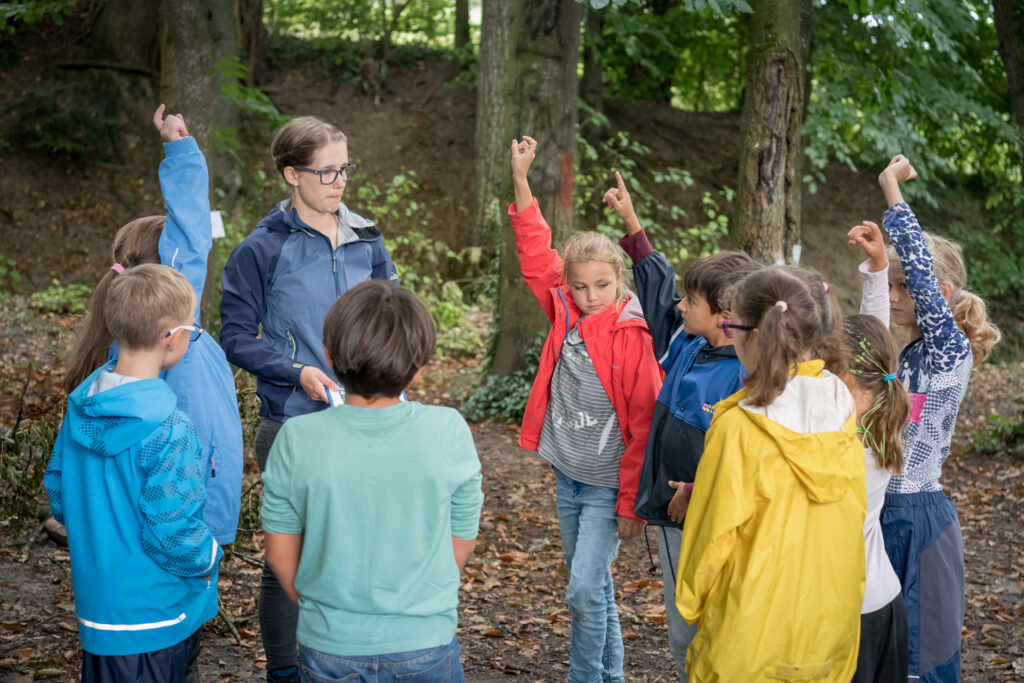 Kinder strecken auf im Kreis stehend im Wald